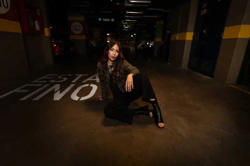 Modelo de la campaña «Está fino» sentada en el parqueadero de VISTO, junto al letrero pintado en el piso
