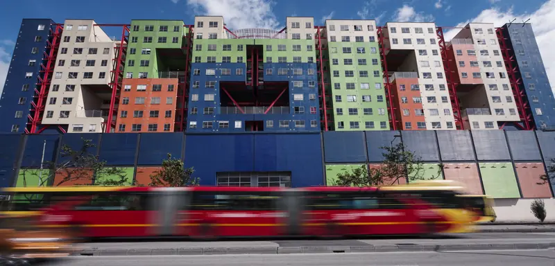 Fachada del Centro Comercial VISTO sobre la Av. Caracas, con su edificio de colores y un bus de TransMilenio en movimiento