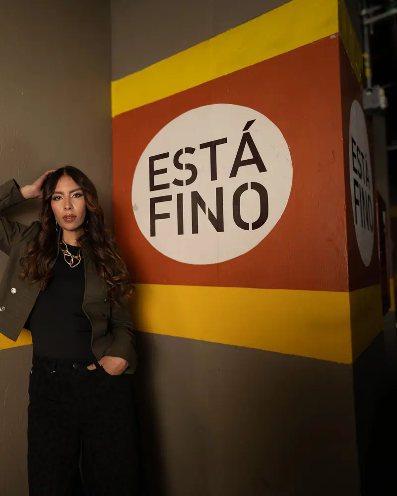 Modelo con chaqueta verde junto al muro «Está fino» del parqueadero