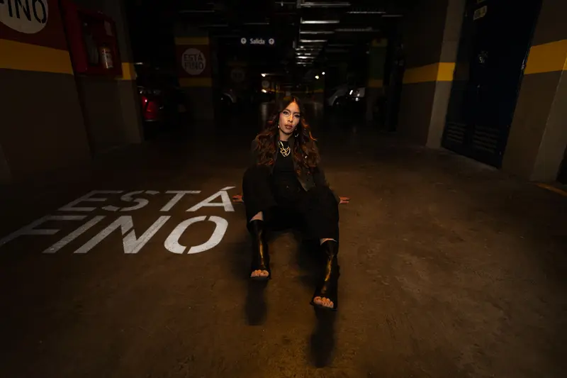 Modelo de la campaña «Está fino» sentada en el piso del parqueadero de VISTO, junto a «ESTÁ FINO» pintado en el suelo